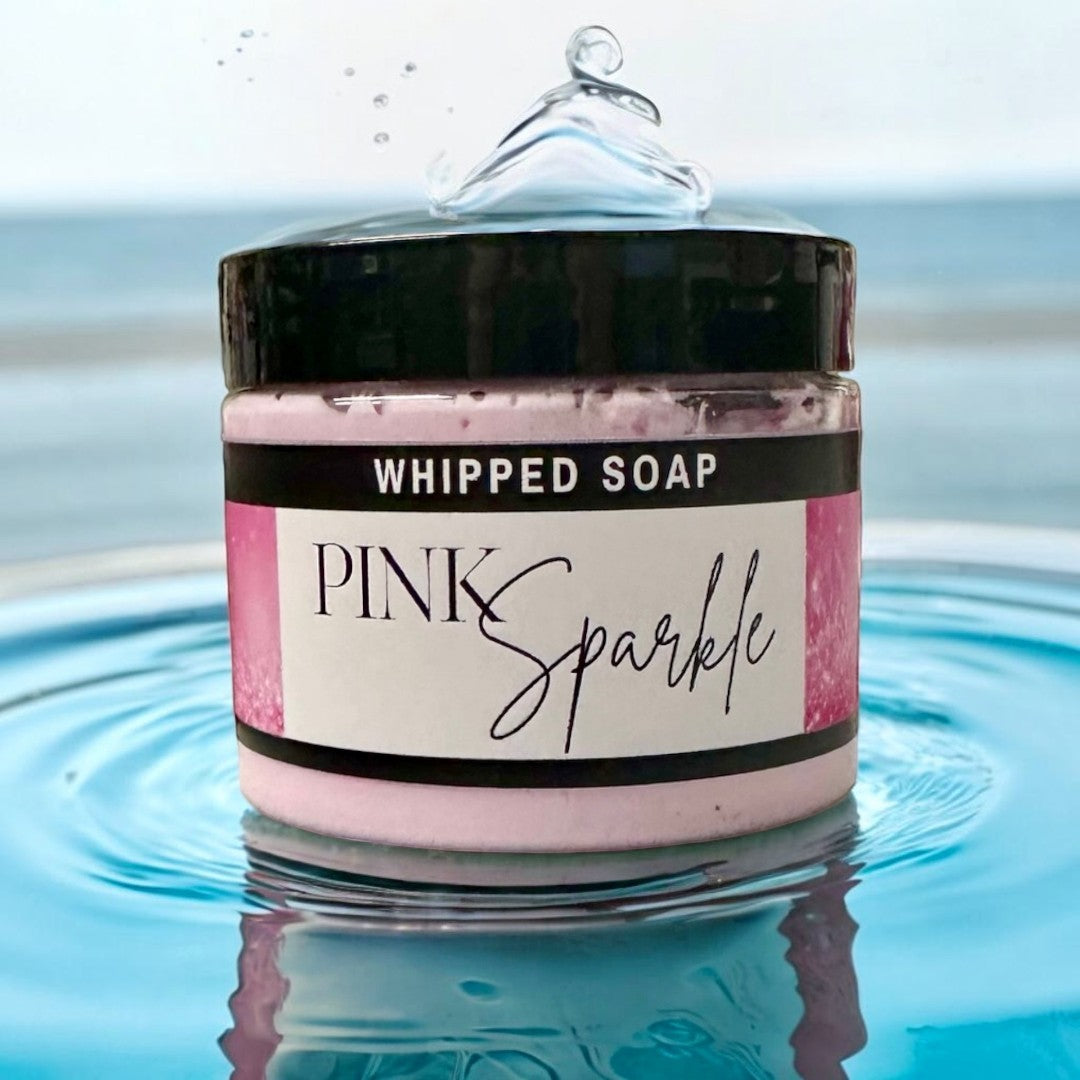 Doodlations Coffee Bar & Boutique Pink Sparkle whipped soap jar in blue water with a splash effect.