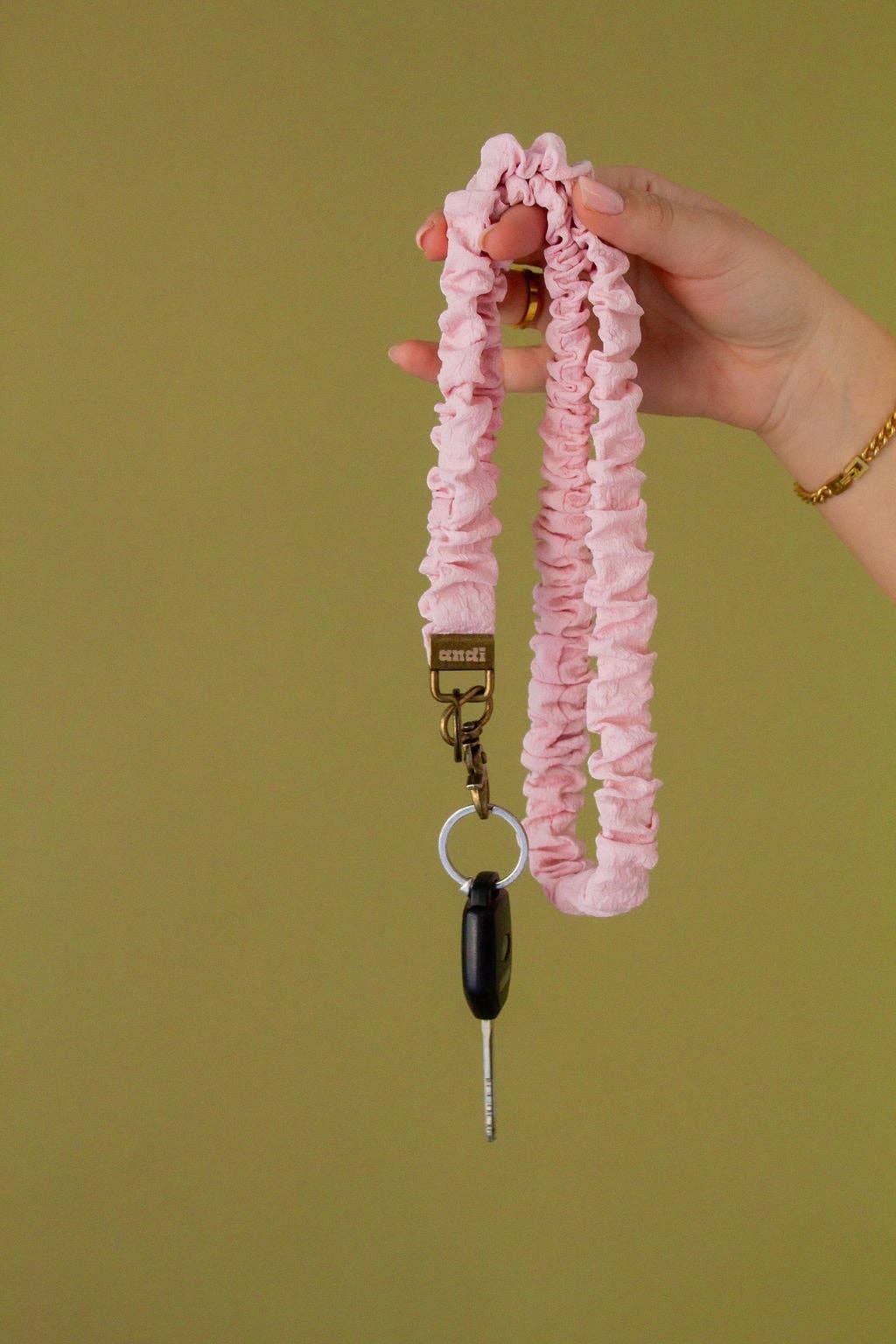 Doodlations Coffee Bar & Boutique light pink textured fabric lanyard with a brass clasp holding a car key