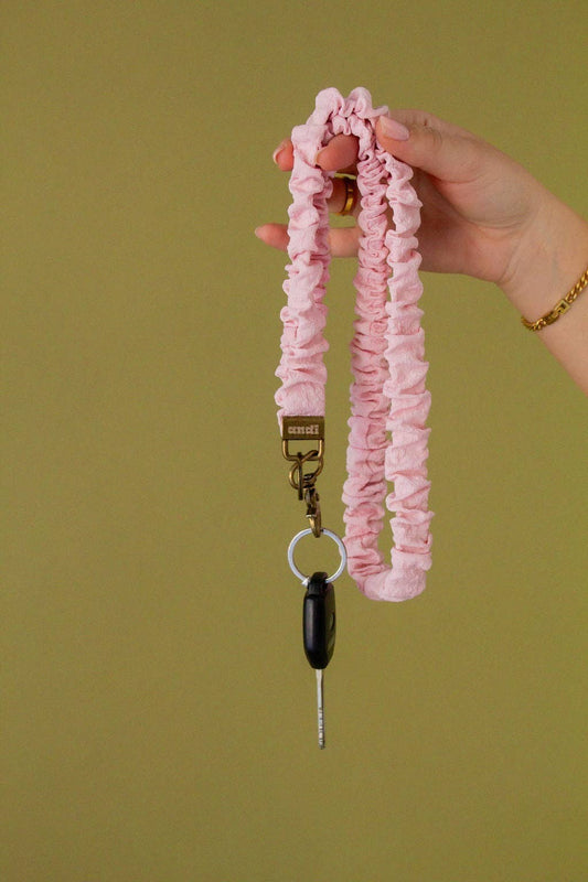 Doodlations Coffee Bar & Boutique light pink textured fabric lanyard with a brass clasp holding a car key