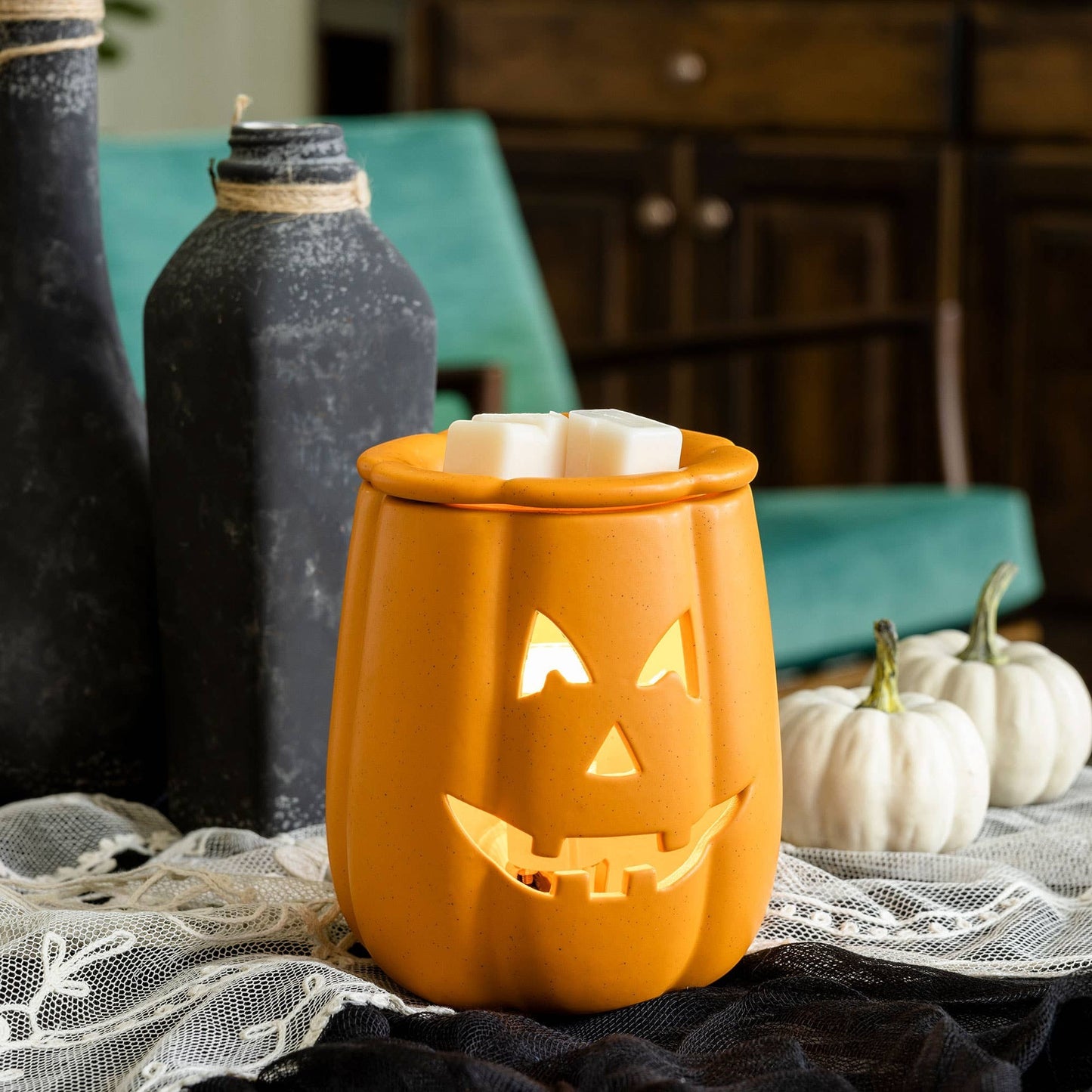 Doodlations Coffee Bar & Boutique orange ceramic Jack o' Lantern wax warmer with glowing face and white wax melts