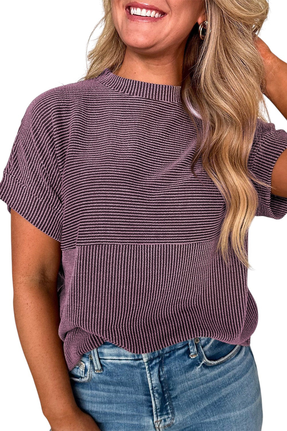 A woman wearing a Doodlations Coffee Bar & Boutique purple ribbed mock neck t-shirt with short sleeves and denim jeans.