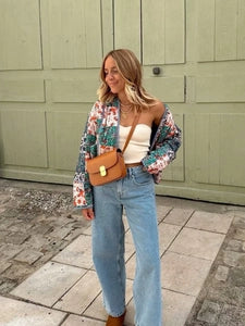 Doodlations Coffee Bar & Boutique quilted patchwork floral jacket worn by a woman with light blue jeans and a tan bag