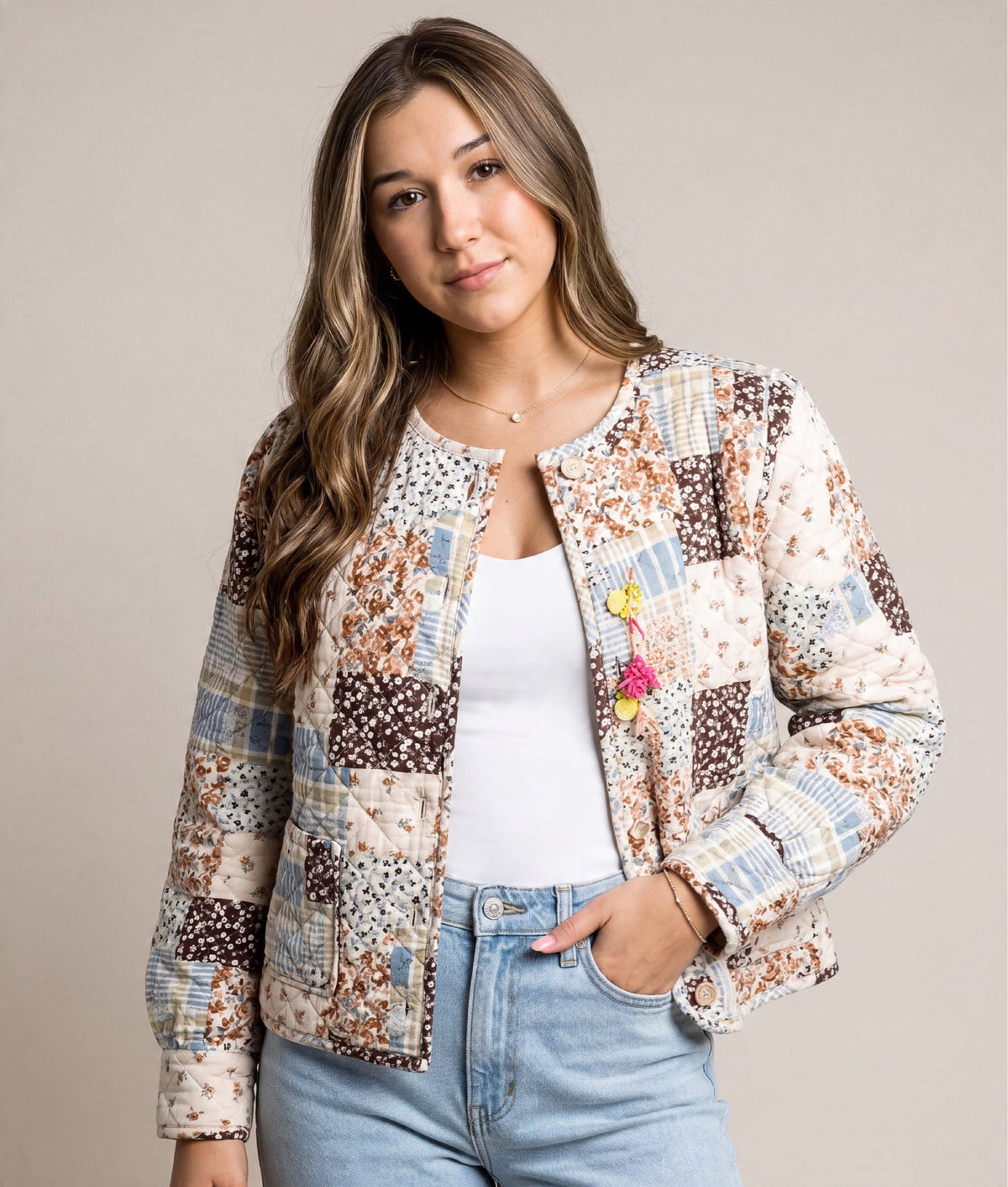 A woman wearing a Doodlations Coffee Bar & Boutique quilted patchwork jacket with floral prints and button closure.