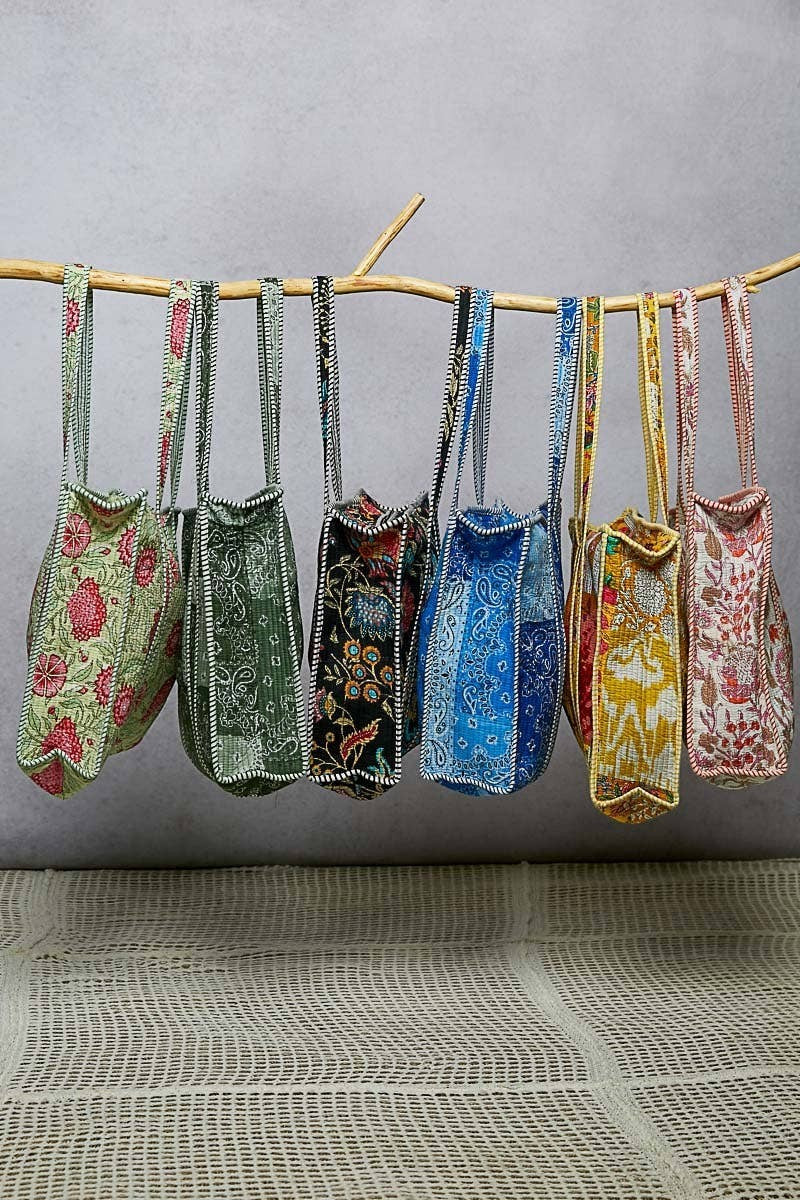 Doodlations Coffee Bar & Boutique quilted tote bags in various floral prints and colors hanging on a wooden branch