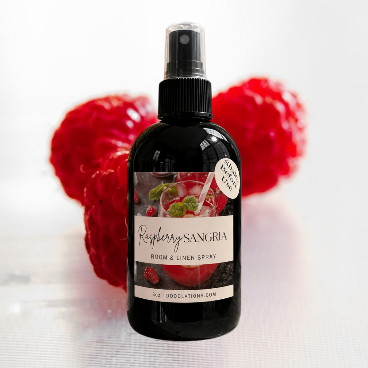 Doodlations Coffee Bar & Boutique Raspberry Sangria room and linen spray in a black bottle with fresh raspberries