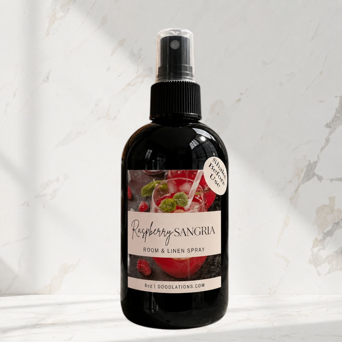 Doodlations Coffee Bar & Boutique Raspberry Sangria room and linen spray in a black bottle with a fruit-themed label.