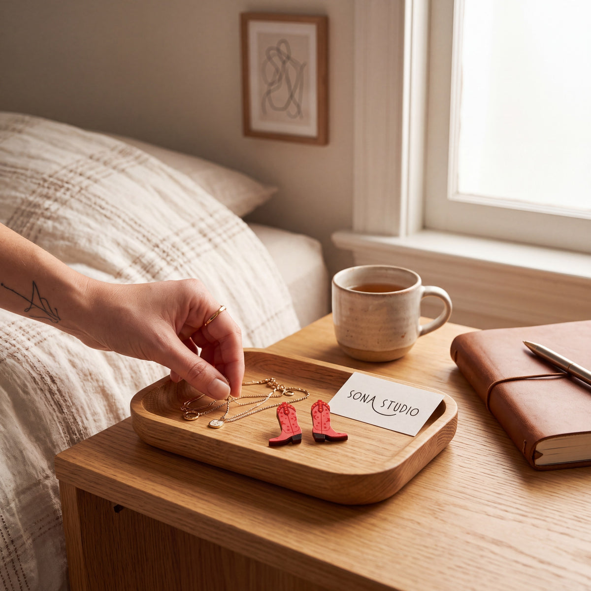 Doodlations Coffee Bar & Boutique red cowgirl boot stud earrings on a wooden tray next to a coffee mug and notebook.
