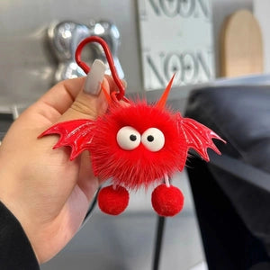 Doodlations Coffee Bar & Boutique plush red bat bag charm with googly eyes and wings held in a hand