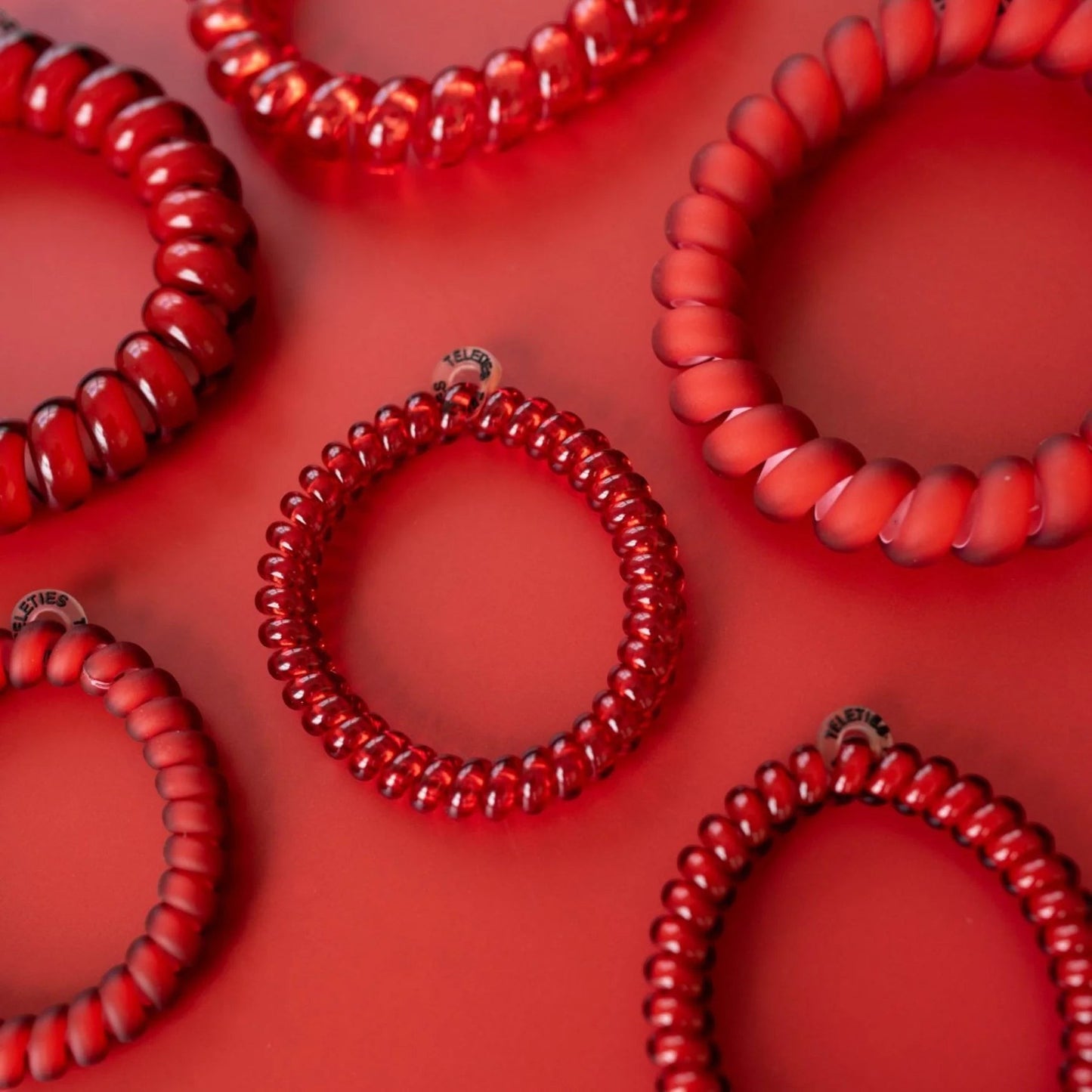 Doodlations Coffee Bar & Boutique red spiral hair ties with a strong, damage-free grip on a matching red background.