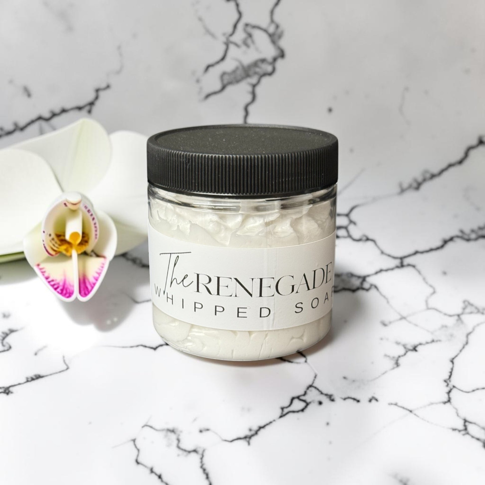 Doodlations Coffee Bar & Boutique The Renegade whipped soap in a clear jar with black lid on a marble surface.