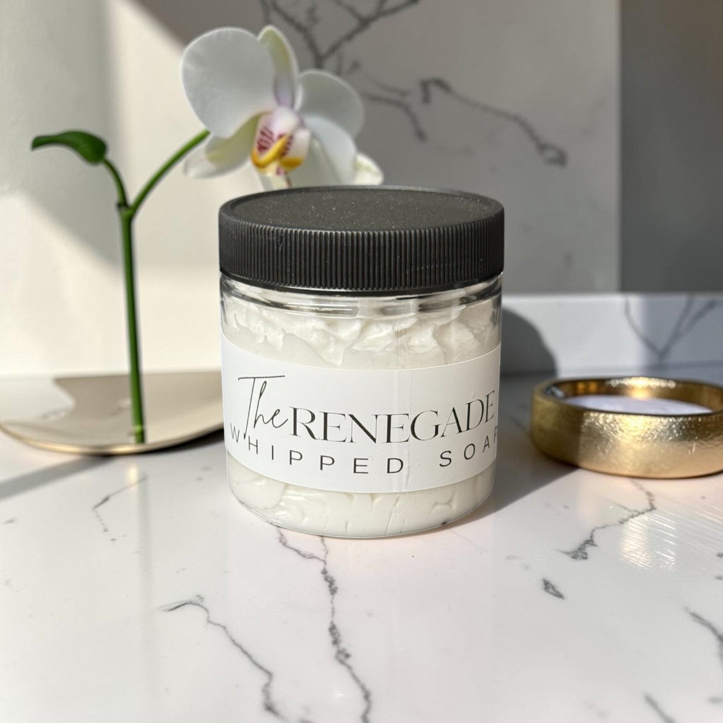 Doodlations Coffee Bar & Boutique The Renegade whipped soap in a clear jar with a black lid on a wooden surface.