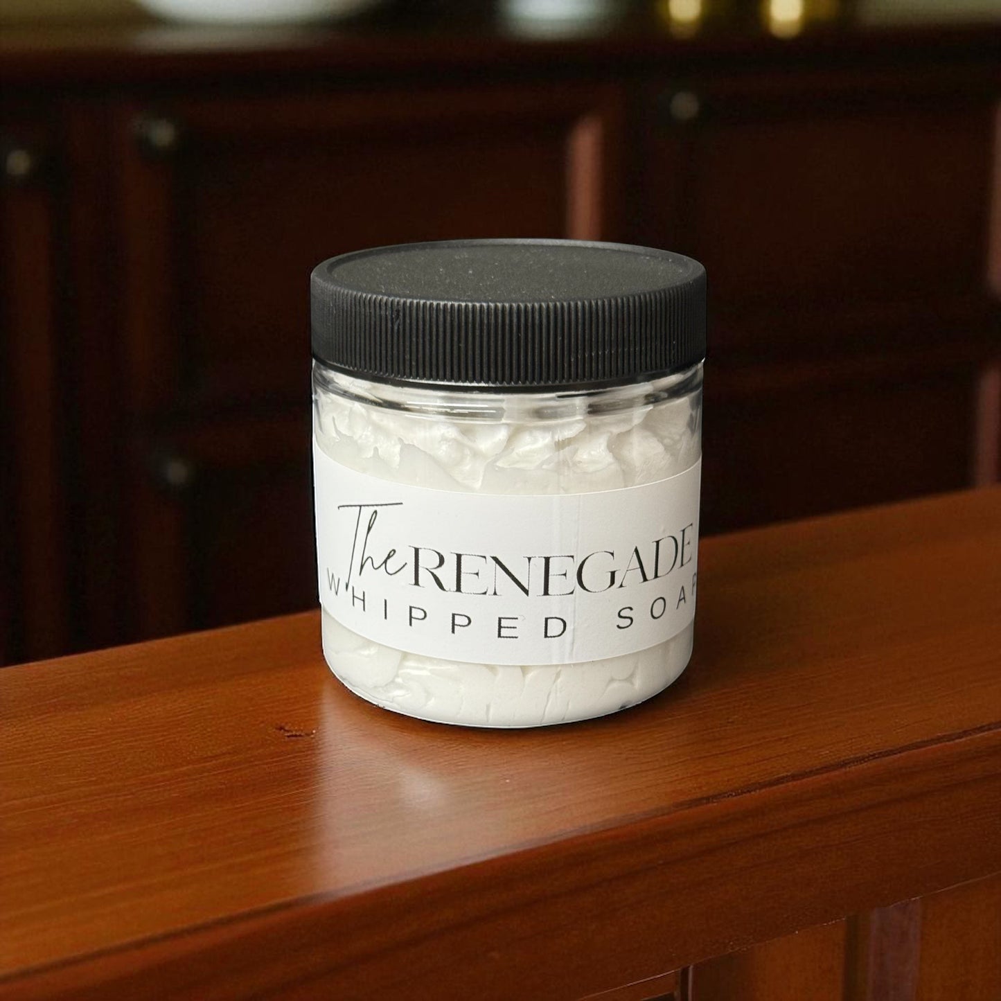 Doodlations Coffee Bar & Boutique The Renegade whipped soap in a clear jar with a black lid on a wooden surface.