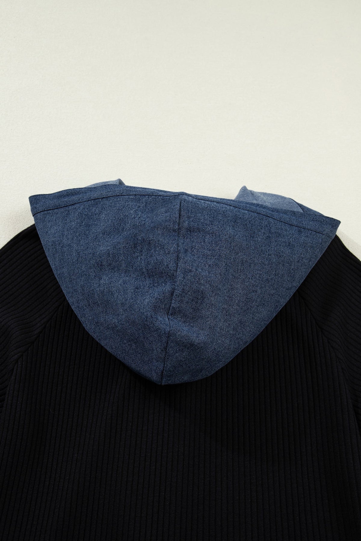 Doodlations Coffee Bar & Boutique black ribbed knit top with a blue denim hood, showing a textured contrast design.