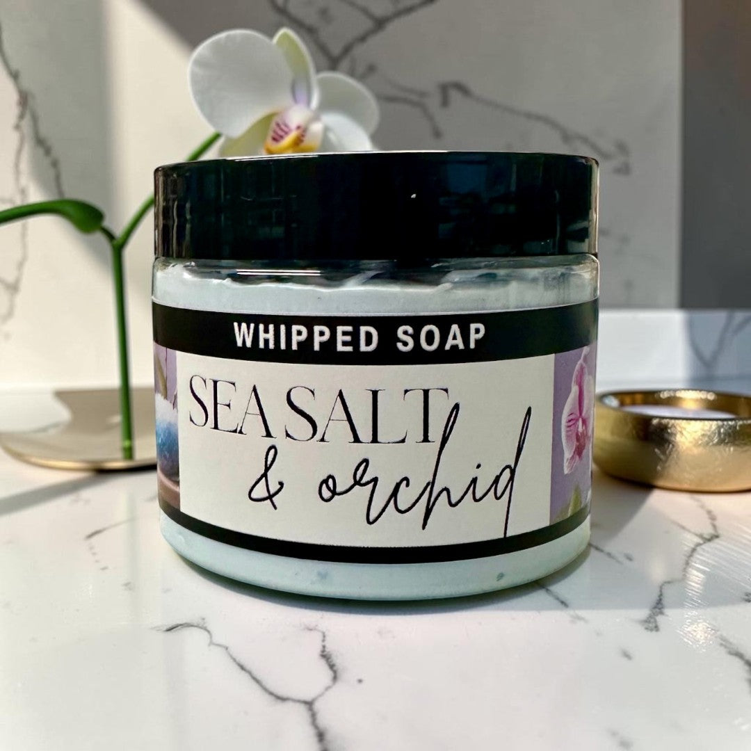 Doodlations Coffee Bar & Boutique Sea Salt & Orchid whipped soap in a jar sitting in blue water ripples.