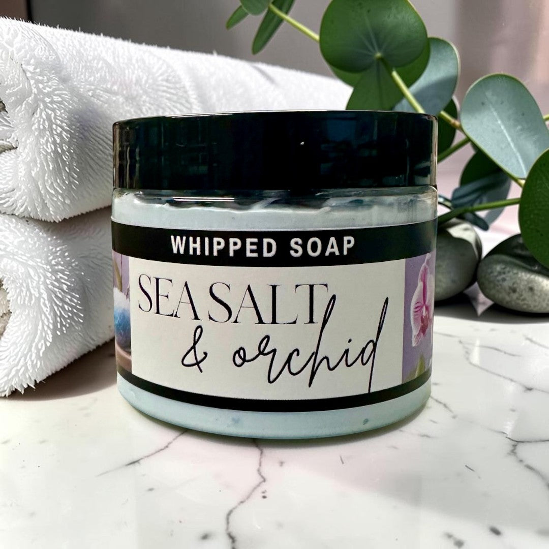 Doodlations Coffee Bar & Boutique Sea Salt & Orchid whipped soap in a jar sitting in blue water ripples.
