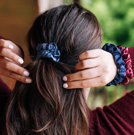 Doodlations Coffee Bar & Boutique Teleties silk scrunchies in navy, burgundy, and steel blue worn in long brown hair.