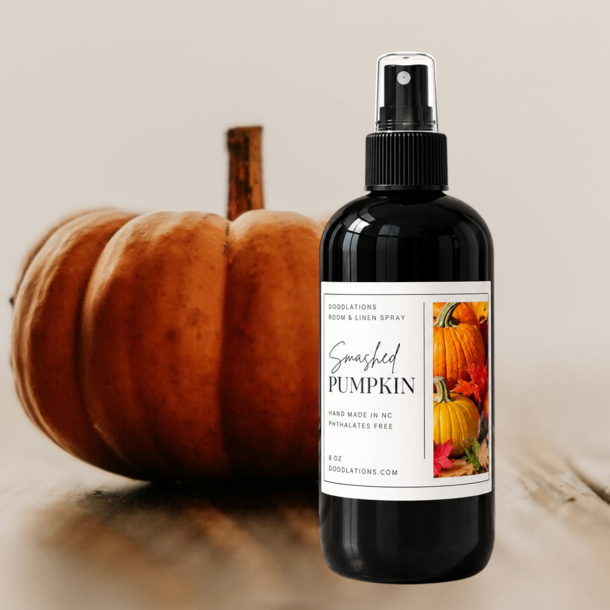 Doodlations Coffee Bar & Boutique Smashed Pumpkin room and linen spray in a black 8oz bottle next to a real pumpkin.