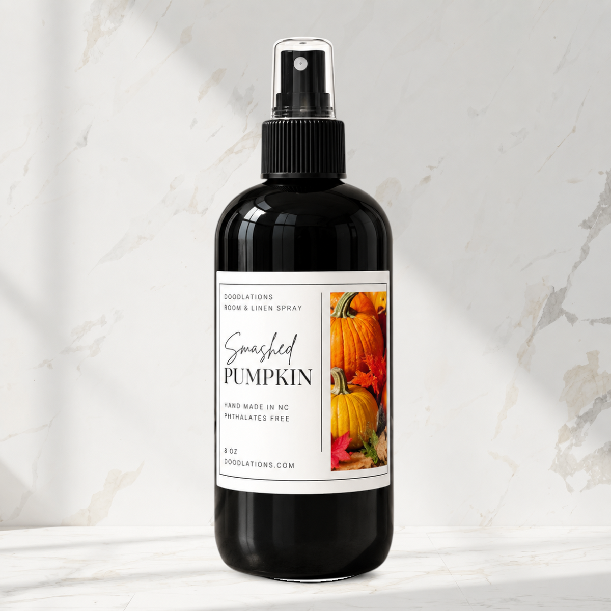 Doodlations Coffee Bar & Boutique Smashed Pumpkin room and linen spray in a black 8oz bottle on a marble surface.