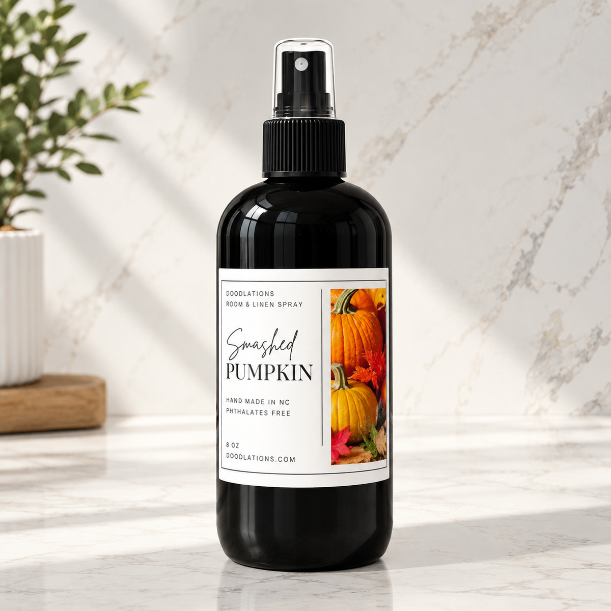 Doodlations Coffee Bar & Boutique Smashed Pumpkin room and linen spray in a black bottle on a marble surface.