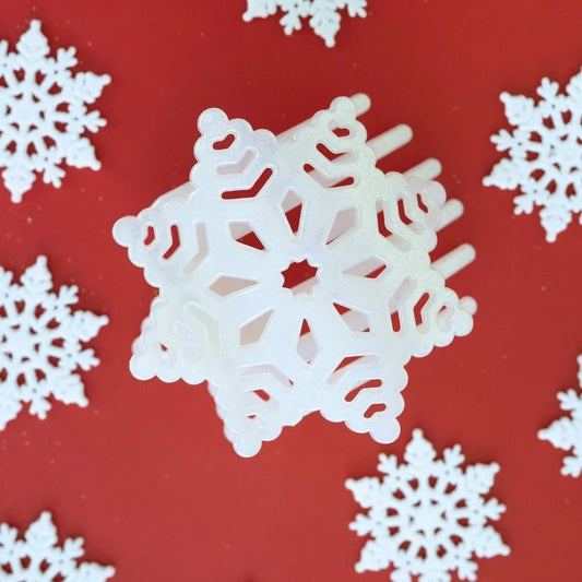 Doodlations Coffee Bar & Boutique white glitter snowflake hair clip with cutout details on a red background
