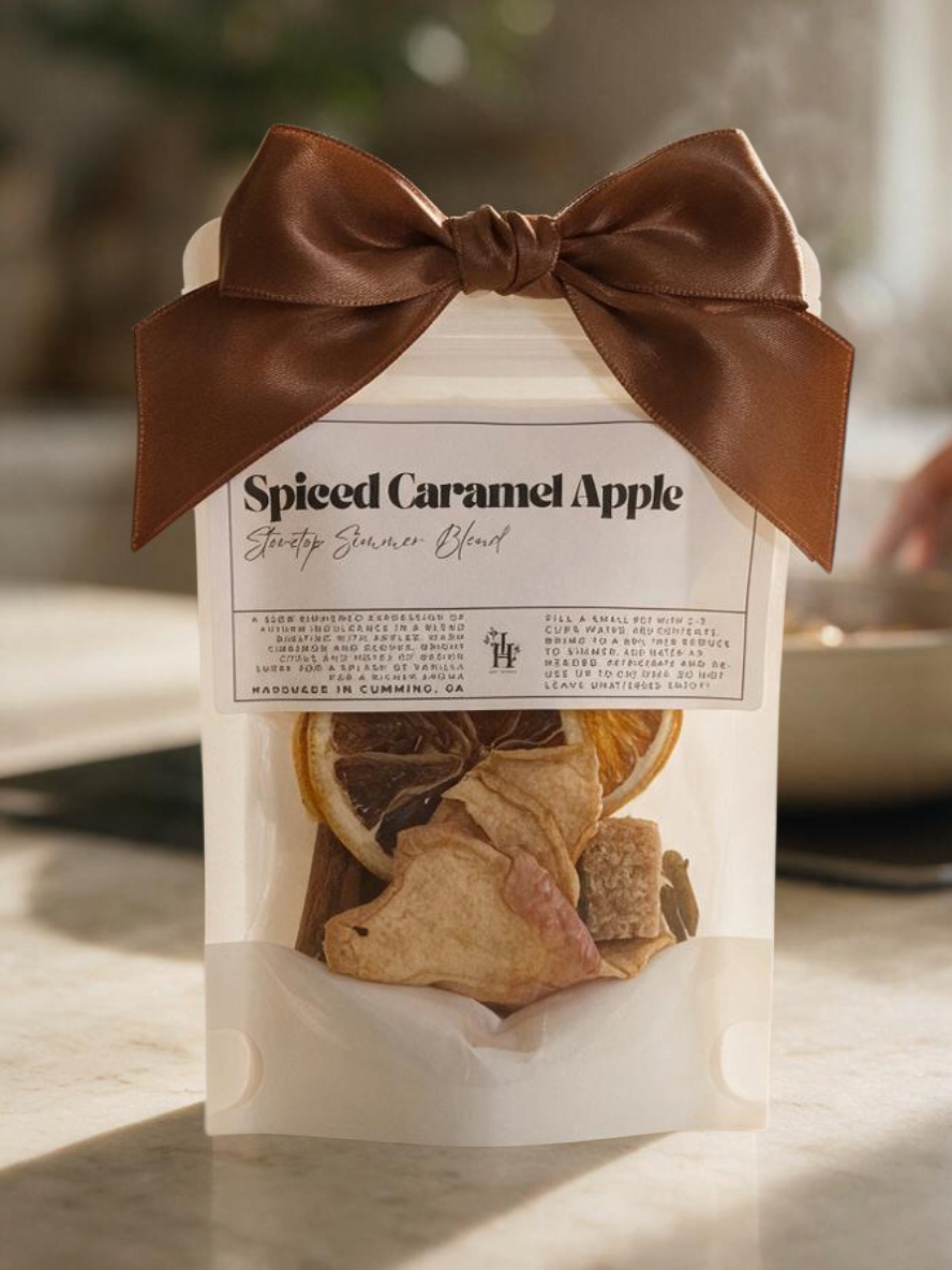 Doodlations Coffee Bar & Boutique Spiced Caramel Apple stovetop simmer blend in a small bag with a brown satin bow.