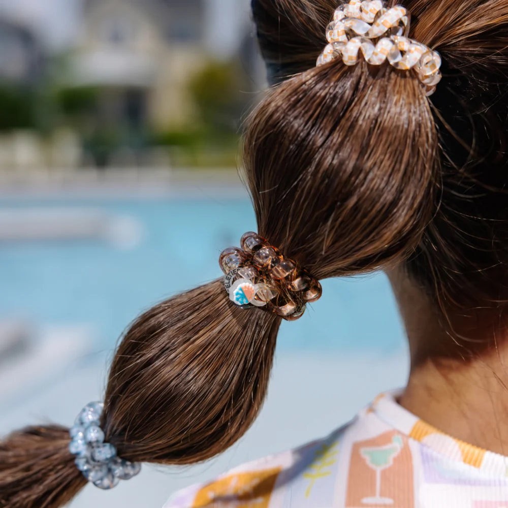 Doodlations Coffee Bar & Boutique Island Threads spiral hair ties in brown and clear worn in a bubble ponytail