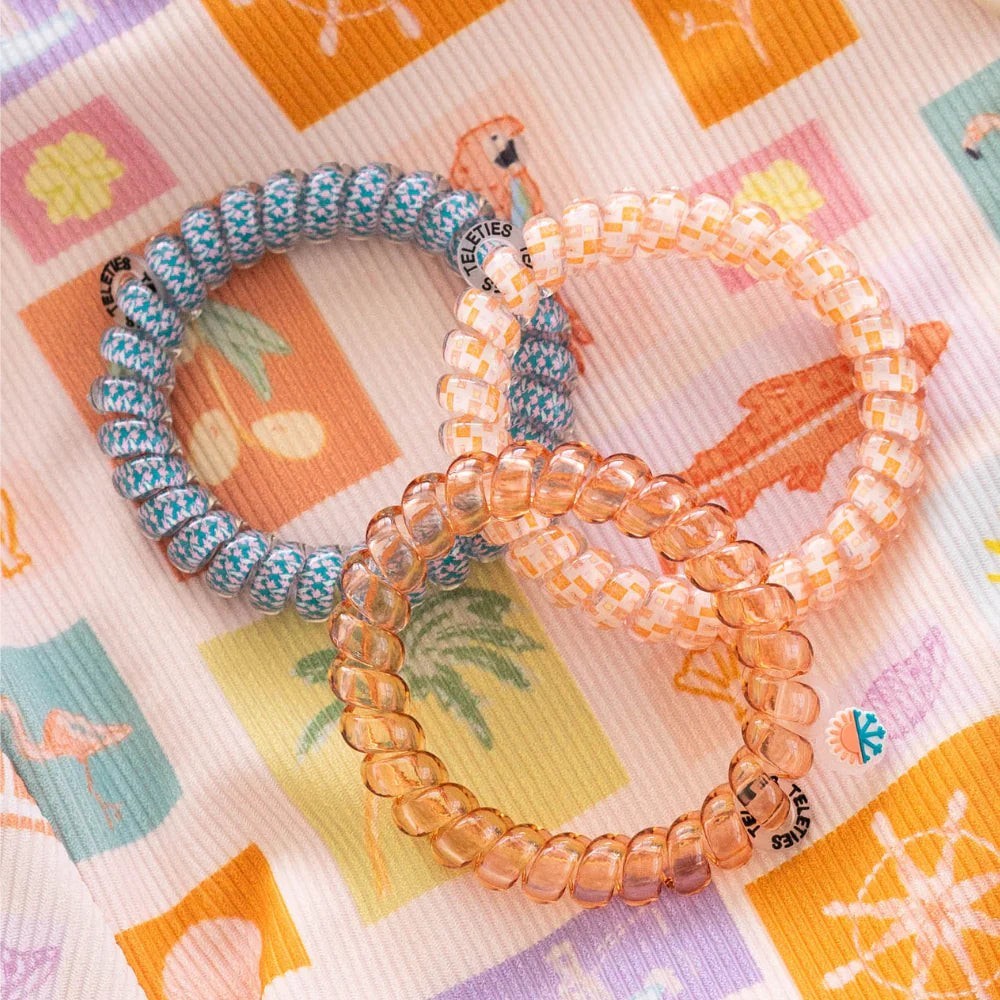 Doodlations Coffee Bar & Boutique Island Threads spiral hair ties in blue, orange, and clear patterns on fabric.