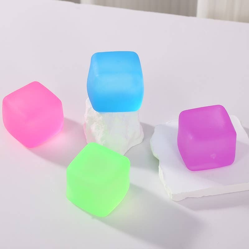 Doodlations Coffee Bar & Boutique squishy cubes in pink, blue, green, and purple. Soft, pliable material for stress relief and sensory play.