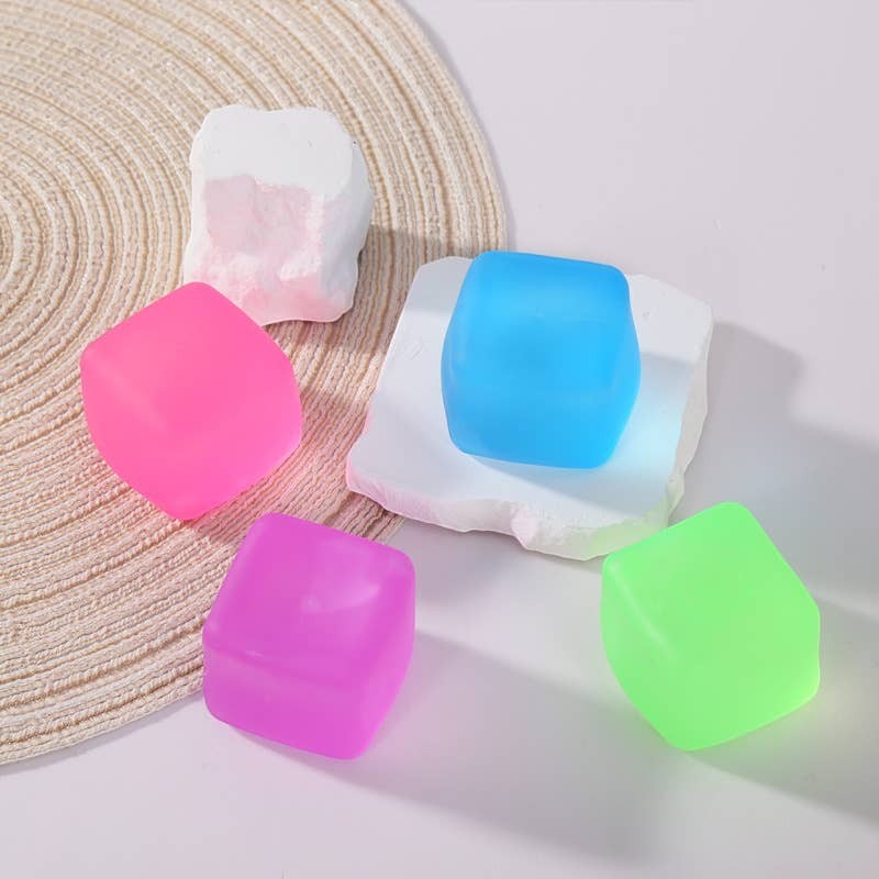 Doodlations Coffee Bar & Boutique squishy cubes in pink, purple, blue, and green. Soft, pliable material for stress relief and sensory play.