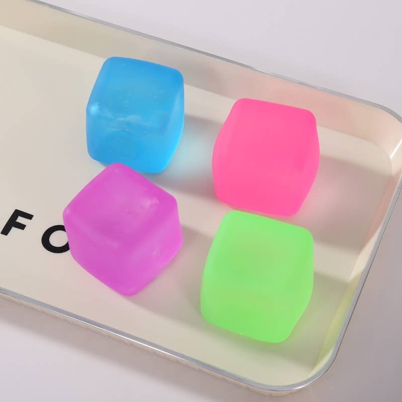 Doodlations Coffee Bar & Boutique squishy cubes in blue, pink, purple, and green. Soft, pliable sensory toys for stress relief and focus.