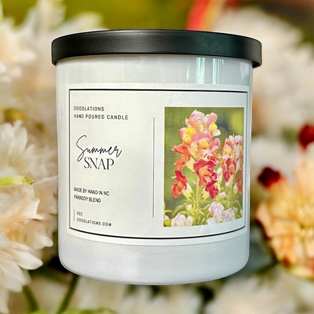 Doodlations Coffee Bar & Boutique Summer Snap hand-poured parasoy blend candle with floral-fruity scent. White jar with black lid.