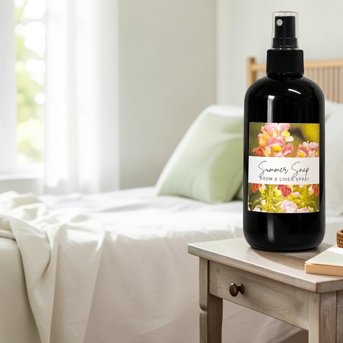 Doodlations Coffee Bar & Boutique Summer Snap room and linen spray in a black bottle on a wooden bedside table.