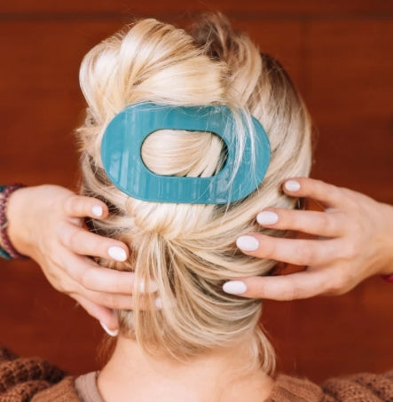 Doodlations Coffee Bar & Boutique teal flat round hair clip securing a blonde updo, designed for comfort.