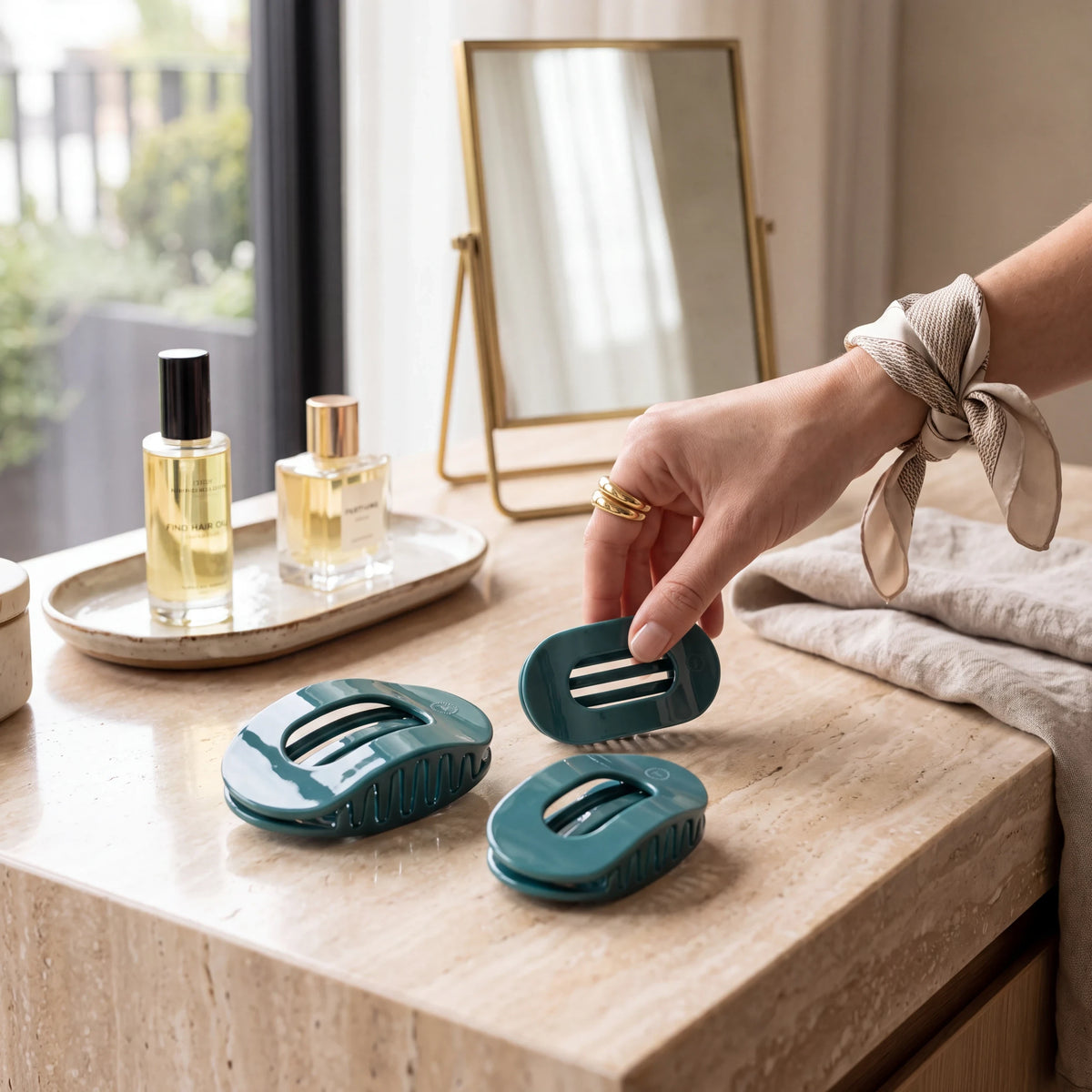 Doodlations Coffee Bar & Boutique teal flat round hair clips on a marble vanity with perfume and a silk scarf