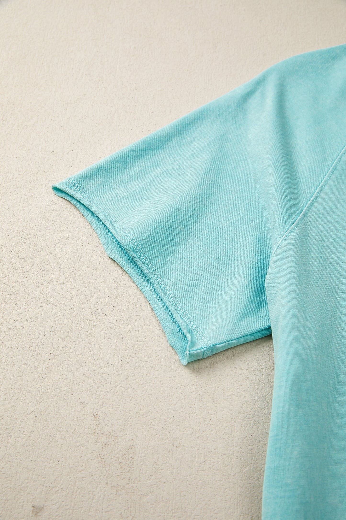 Doodlations Coffee Bar & Boutique teal mineral wash cotton blend tee with raw edge hem and sleeves.