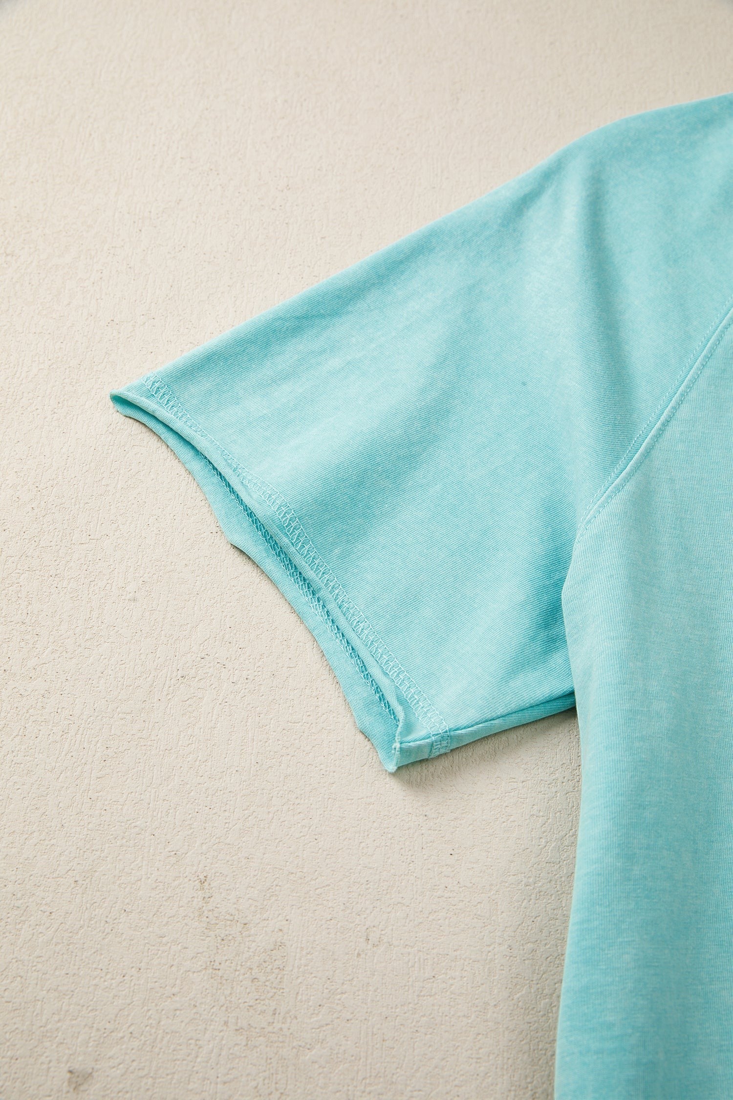 Doodlations Coffee Bar & Boutique teal mineral wash cotton blend tee with raw edge hem and sleeves.