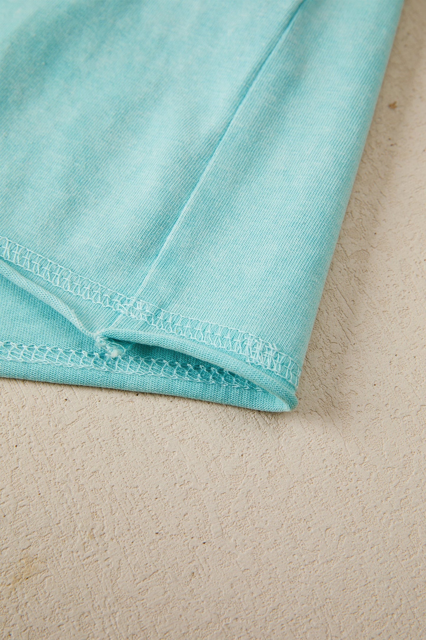 Doodlations Coffee Bar & Boutique teal mineral wash cotton blend relaxed fit tee with raw edge hem and sleeves.