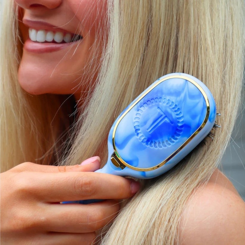 Doodlations Coffee Bar & Boutique Teleties boar bristle hair brush with a blue marble pattern held by a blonde woman
