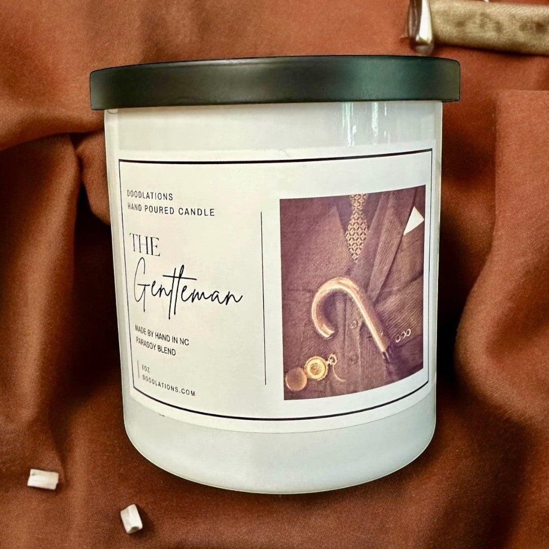 Doodlations Coffee Bar & Boutique The Gentleman luxury hand-poured soy blend candle with masculine cologne scent. White jar.