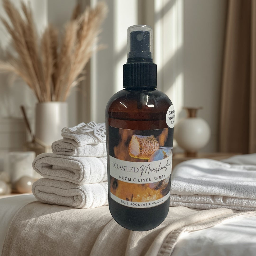 Doodlations Coffee Bar & Boutique Toasted Marshmallow room and linen spray in amber bottle with black spray top. Features image of toasted marshmallows.