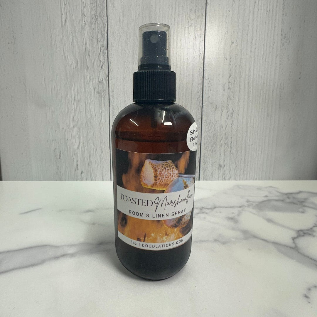 Doodlations Coffee Bar & Boutique Toasted Marshmallow room and linen spray in amber bottle with black spray top.