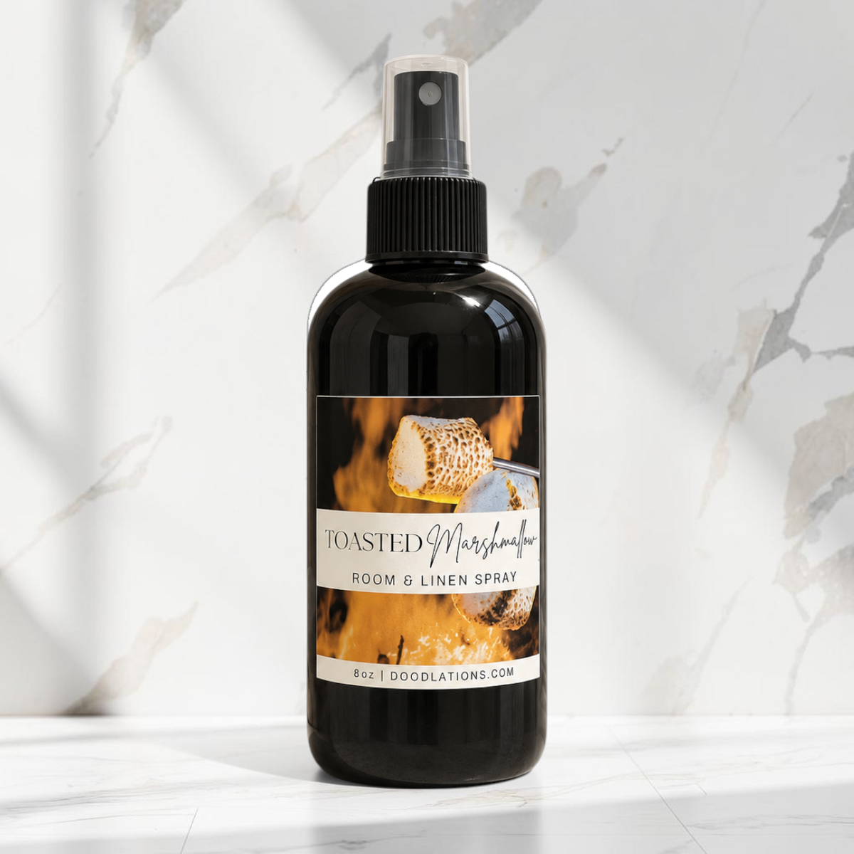 Doodlations Coffee Bar & Boutique Toasted Marshmallow room and linen spray in a black bottle on a marble surface.