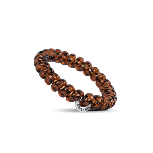 Doodlations Coffee Bar & Boutique tortoise shell spiral hair tie with a silver charm on a black background