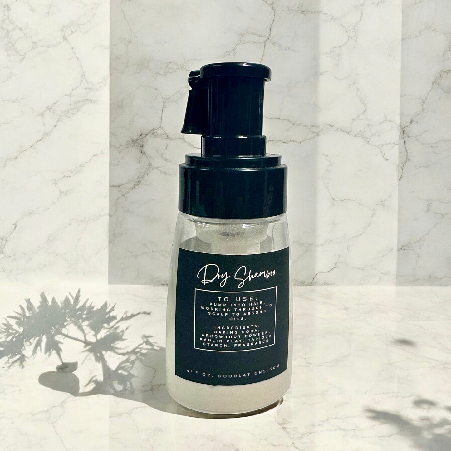 Doodlations Coffee Bar & Boutique Vampire Blood dry shampoo in a clear pump bottle with a black label on marble.