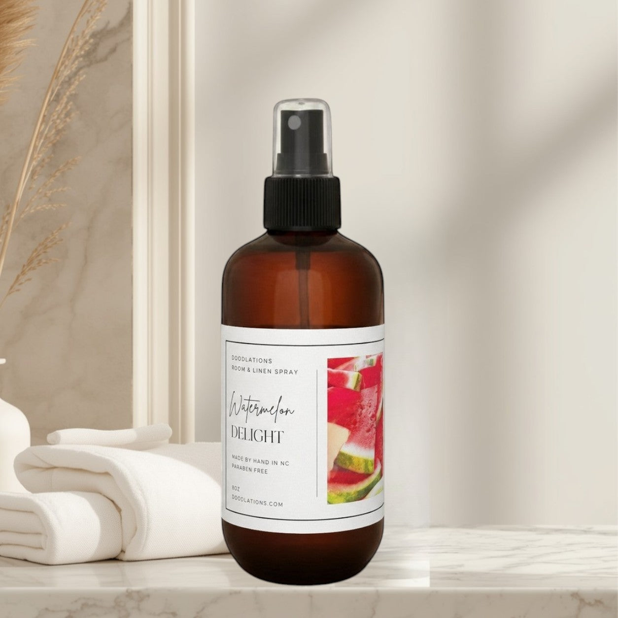 Doodlations Coffee Bar & Boutique Watermelon Delight room and linen spray in an amber bottle on a wooden floor.