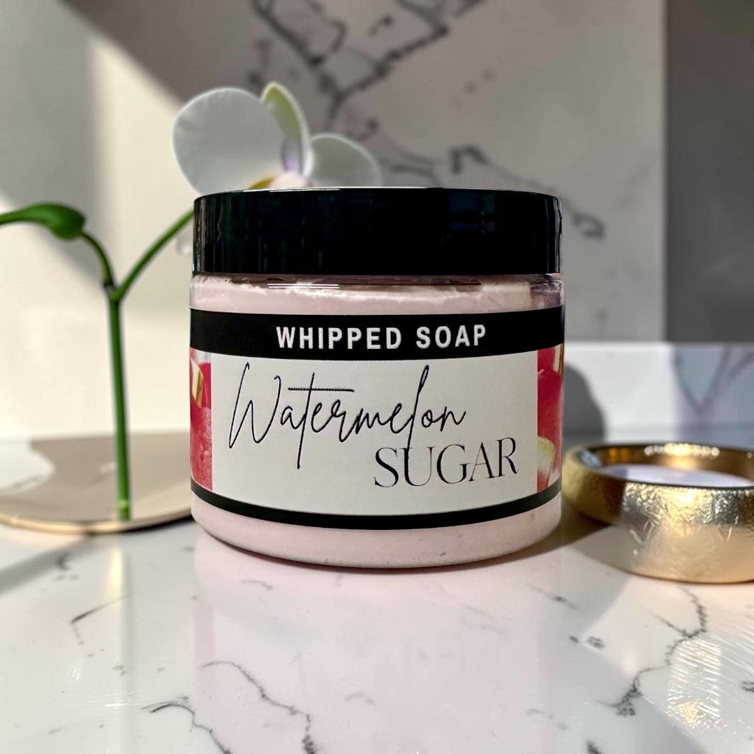 Doodlations Coffee Bar & Boutique Watermelon Sugar whipped soap in a jar with a white orchid on marble background.