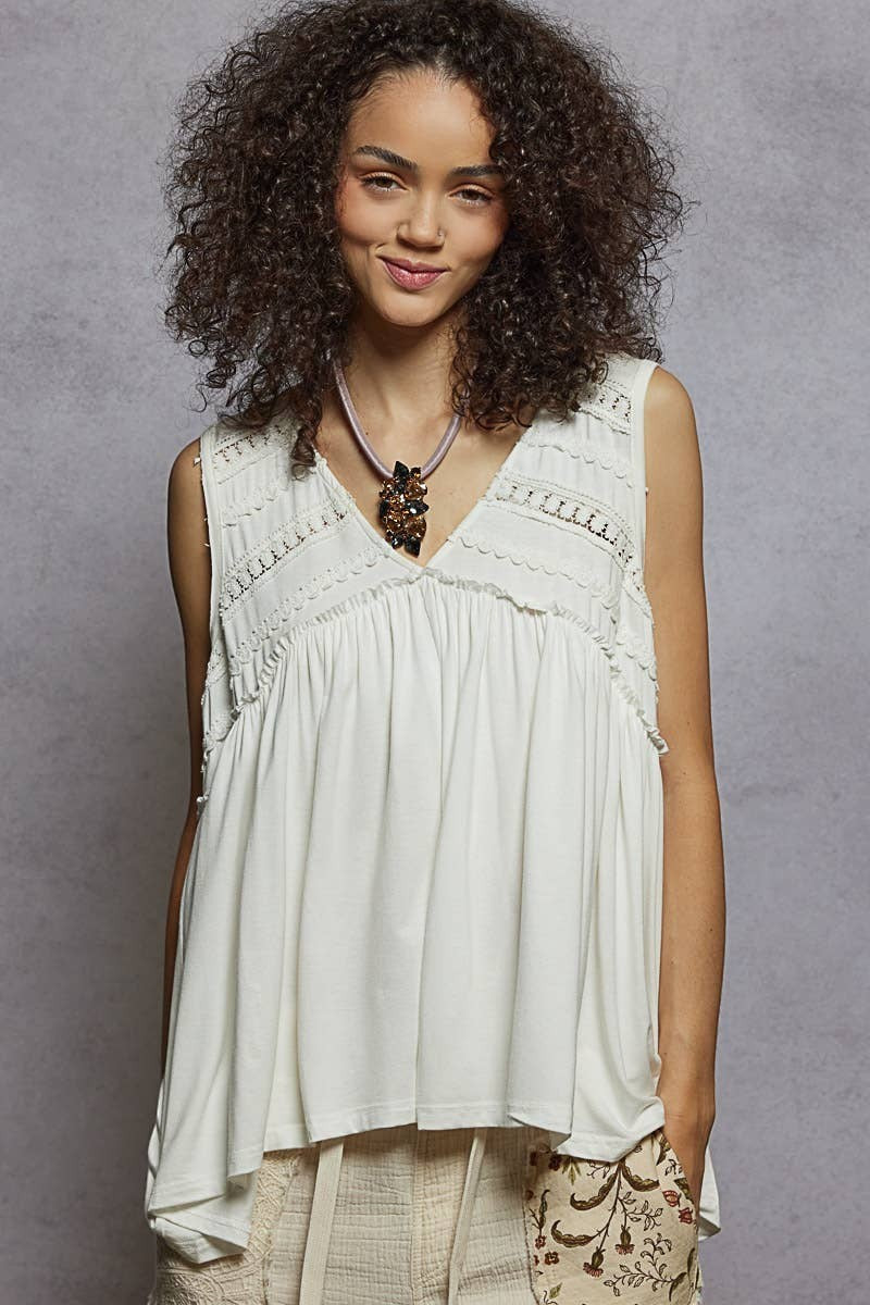 Doodlations Coffee Bar & Boutique sleeveless white babydoll knit top with lace trim, V-neck, and ruffle details.