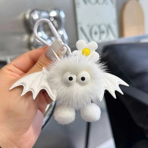 Doodlations Coffee Bar & Boutique white plush bat bag charm with faux fur, googly eyes, and a small flower detail.