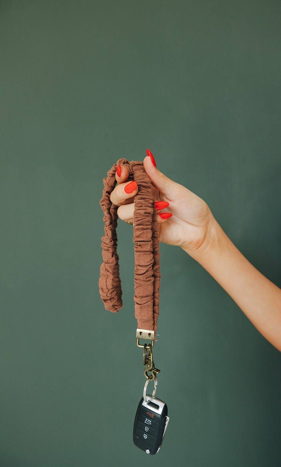 Doodlations Coffee Bar & Boutique Woodland Lanyard in light brown textured fabric held in a hand with car keys