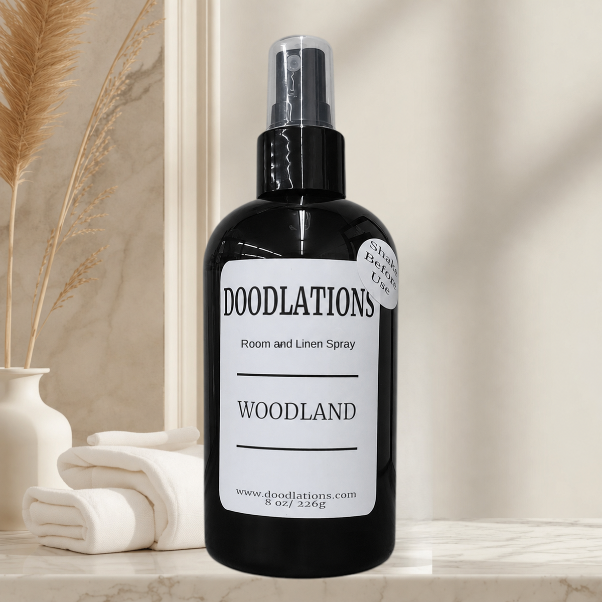 Doodlations Coffee Bar & Boutique Woodland room and linen spray in a black bottle on a marble surface with towels.